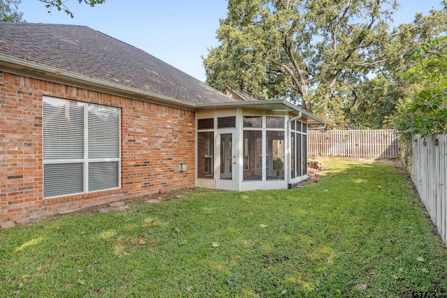 rear view of property with a lawn and a sunroom