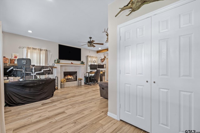 living room featuring a fireplace, ceiling fan, and light hardwood / wood-style flooring