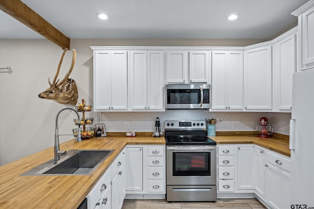 kitchen with stainless steel appliances, butcher block counters, and white cabinetry