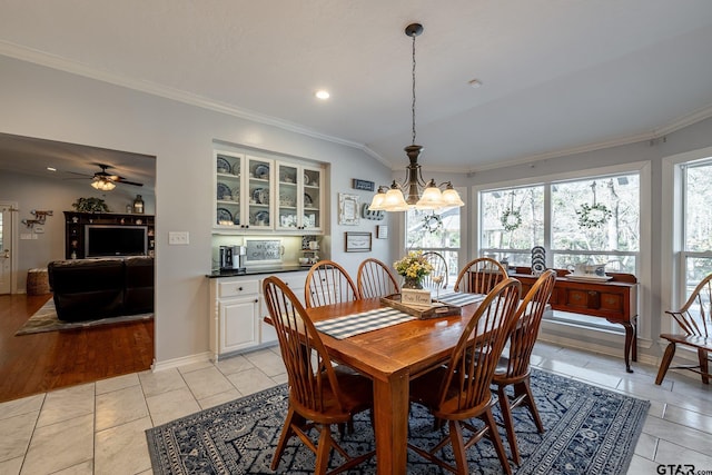 dining area with light tile patterned flooring, ornamental molding, and ceiling fan with notable chandelier