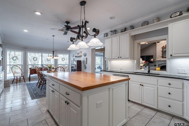 kitchen featuring sink, white cabinetry, a kitchen island, pendant lighting, and ceiling fan