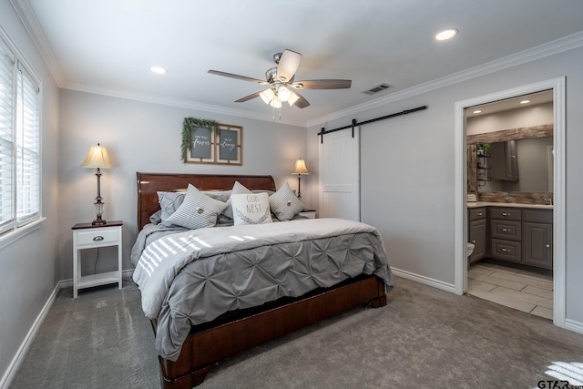 bedroom with connected bathroom, dark colored carpet, ornamental molding, ceiling fan, and a barn door