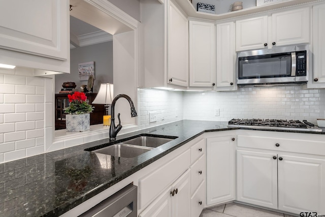 kitchen featuring stainless steel appliances, white cabinetry, sink, and backsplash