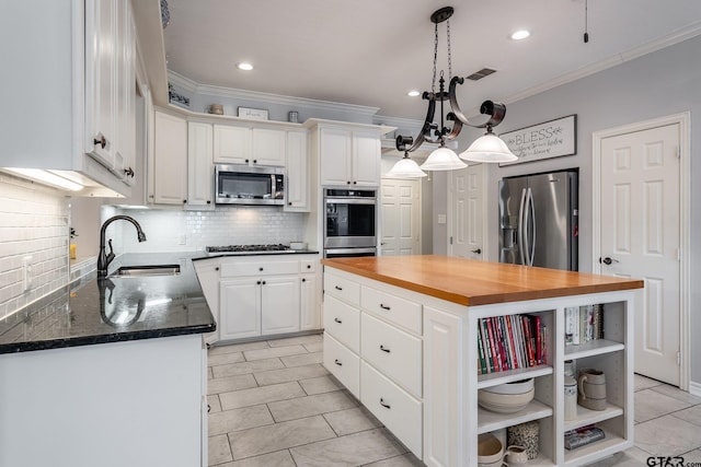 kitchen featuring a kitchen island, appliances with stainless steel finishes, white cabinetry, wooden counters, and backsplash