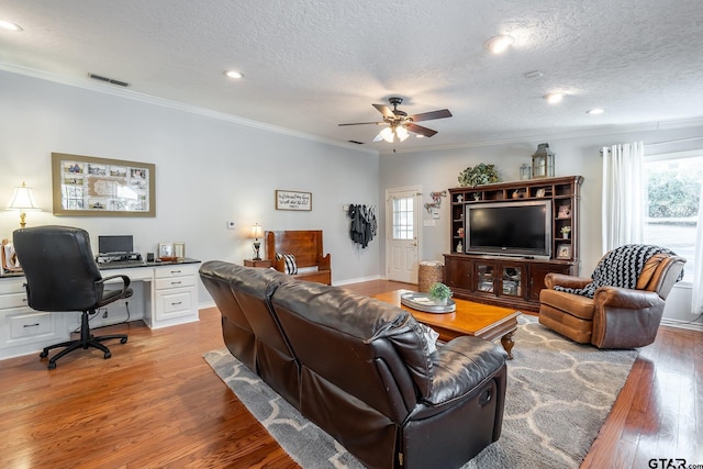 living room with crown molding, ceiling fan, a textured ceiling, and light wood-type flooring