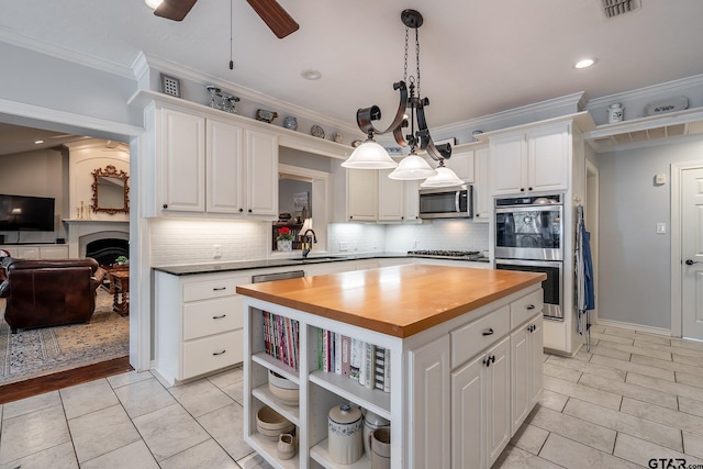 kitchen featuring butcher block counters, white cabinetry, decorative light fixtures, and appliances with stainless steel finishes