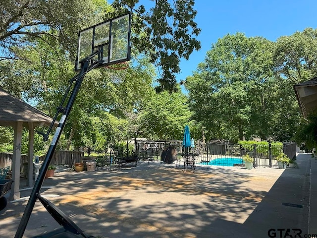 view of sport court with a fenced in pool