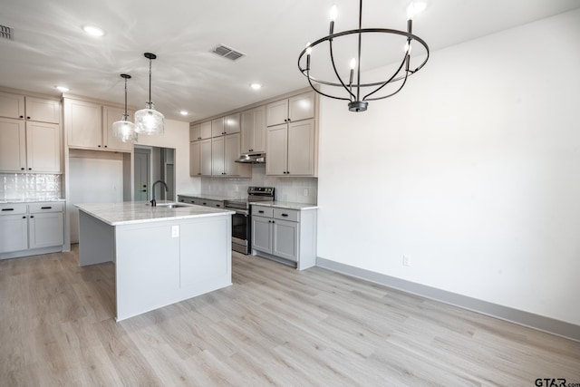 kitchen with pendant lighting, stainless steel electric range oven, a kitchen island with sink, gray cabinetry, and light wood-type flooring