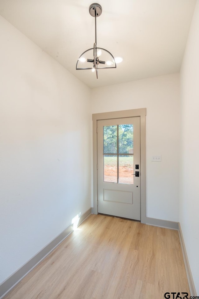 doorway to outside with a chandelier and light hardwood / wood-style floors