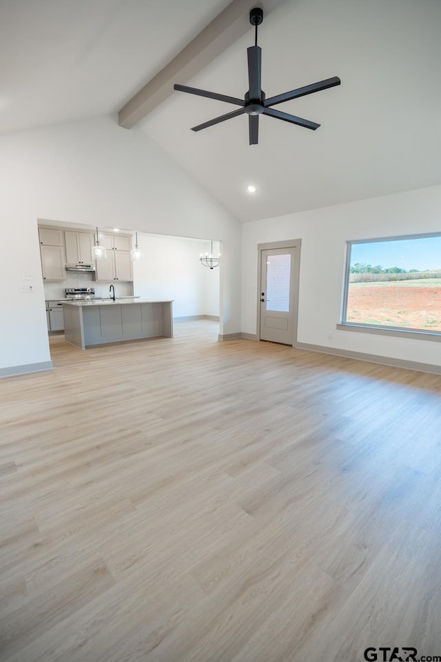 unfurnished living room featuring light hardwood / wood-style floors, sink, ceiling fan with notable chandelier, beam ceiling, and high vaulted ceiling