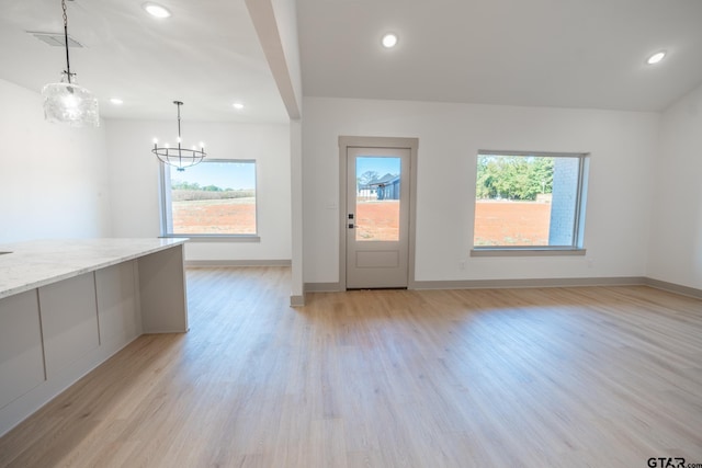 empty room featuring light wood-type flooring and a notable chandelier