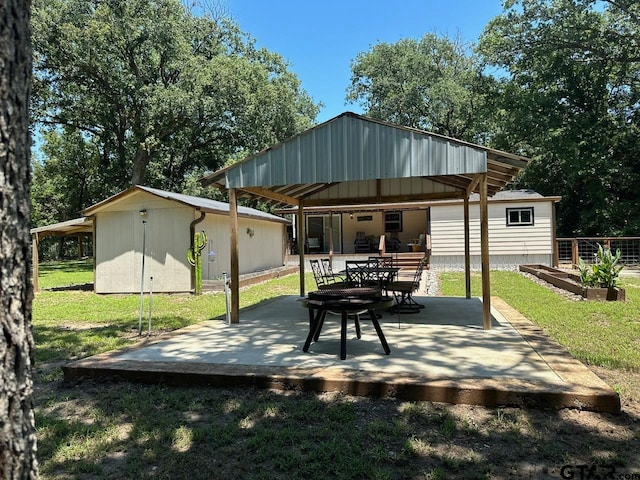 rear view of house featuring an outdoor structure, a lawn, and a patio area