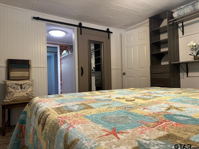 bedroom featuring a barn door, hardwood / wood-style flooring, and ornamental molding