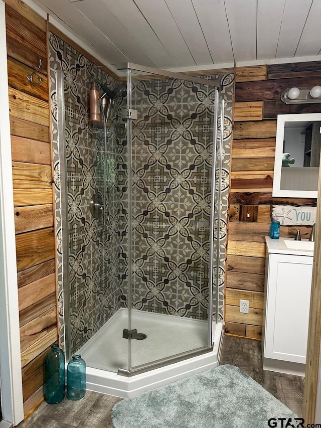 bathroom with hardwood / wood-style floors, vanity, wooden walls, and a shower with door