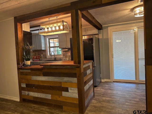 bar with decorative backsplash, sink, dark hardwood / wood-style floors, beam ceiling, and wood counters