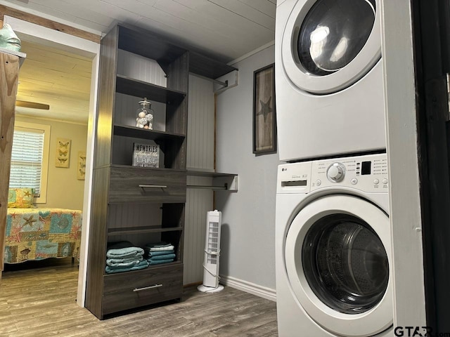 clothes washing area featuring ornamental molding, hardwood / wood-style flooring, and stacked washer / dryer