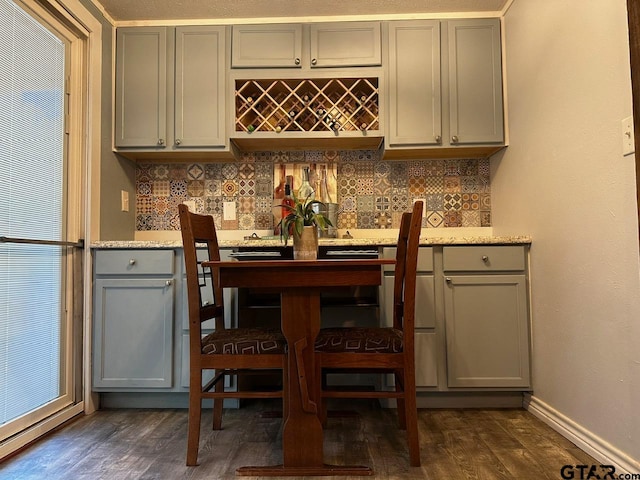 bar featuring decorative backsplash, dark hardwood / wood-style flooring, and light stone countertops