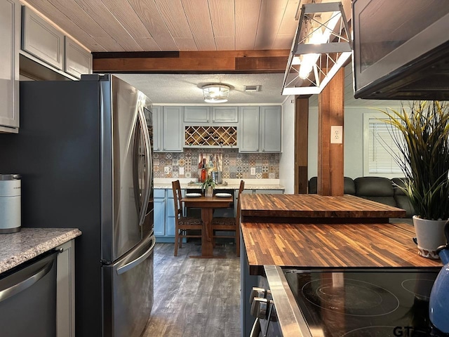 kitchen with stainless steel appliances, backsplash, dark wood-type flooring, gray cabinets, and butcher block countertops