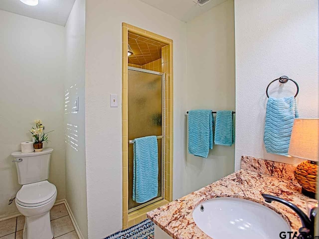 bathroom featuring tile patterned flooring, vanity, a shower with shower door, and toilet