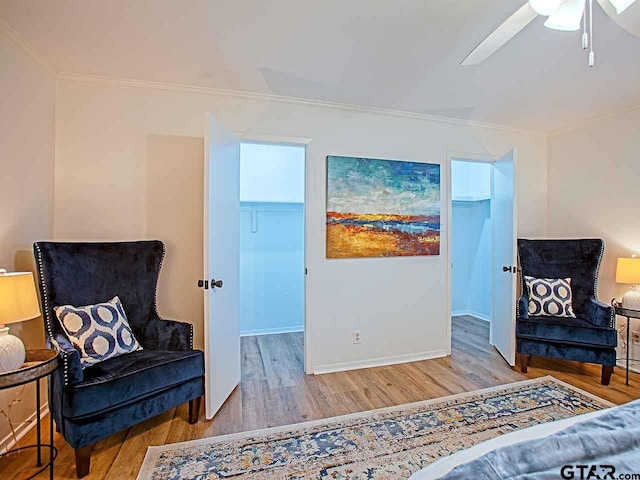 sitting room featuring ceiling fan, light wood-type flooring, and crown molding