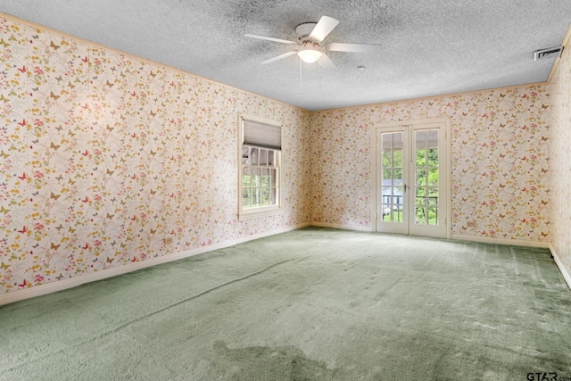 carpeted empty room featuring a wealth of natural light, ceiling fan, and a textured ceiling