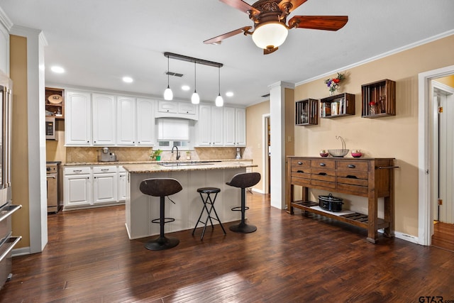 kitchen featuring dark wood-type flooring, a kitchen island, light stone counters, and white cabinets