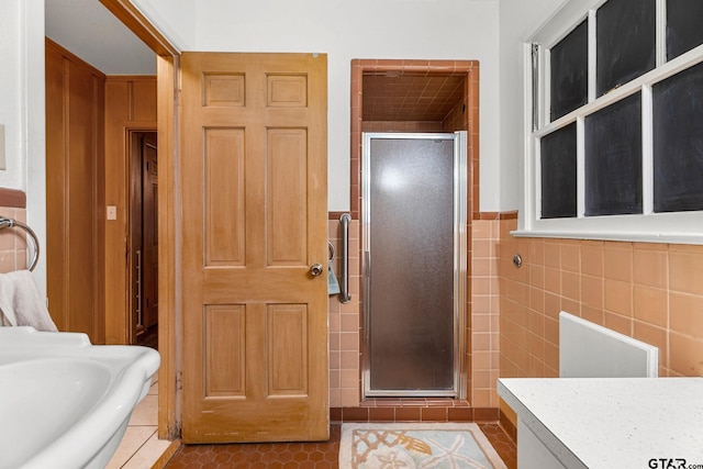 bathroom with a shower with door, tile patterned floors, and tile walls