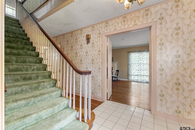 staircase featuring a textured ceiling, ornamental molding, and hardwood / wood-style flooring