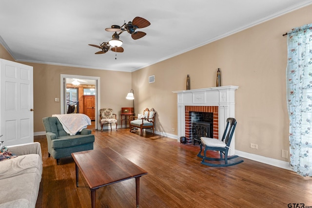 living room featuring a fireplace, dark hardwood / wood-style flooring, ceiling fan, and crown molding