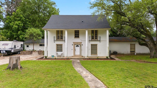 view of front of house featuring central air condition unit, a front yard, and a balcony