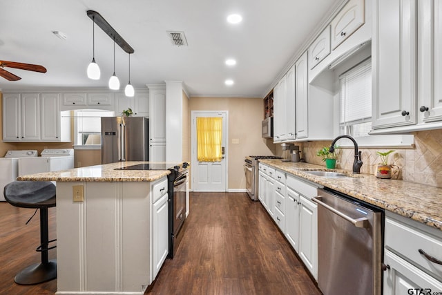 kitchen featuring high end appliances, separate washer and dryer, white cabinets, and a center island