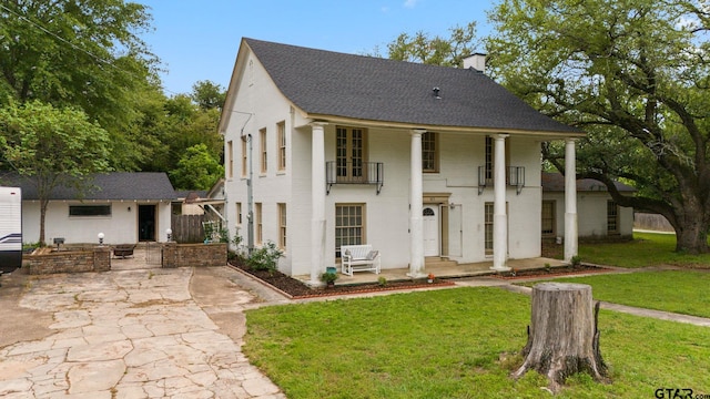 view of front facade featuring a patio, a front yard, and a balcony