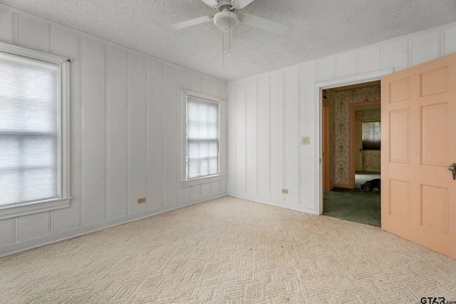 carpeted empty room with ceiling fan and a textured ceiling