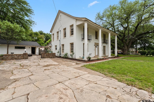 view of side of home featuring a lawn, a patio, and a balcony