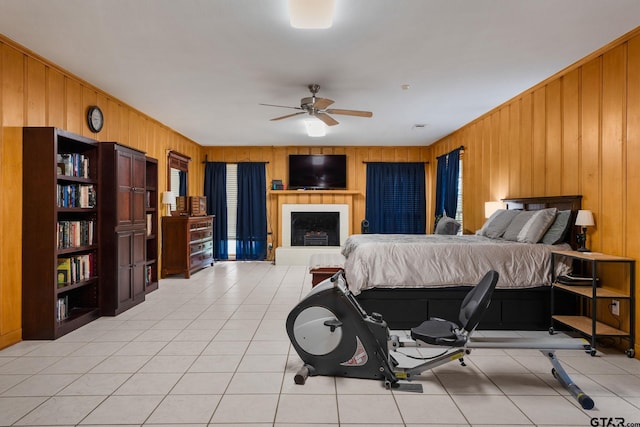 bedroom with wooden walls, ceiling fan, and light tile patterned flooring