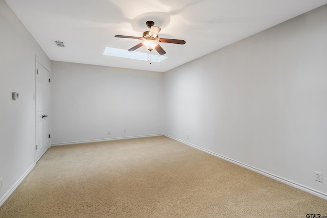 carpeted empty room featuring ceiling fan and a skylight