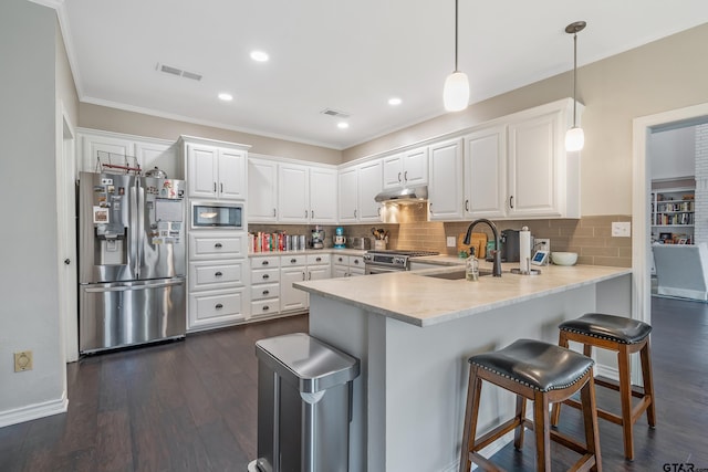 kitchen with white cabinets, appliances with stainless steel finishes, sink, and decorative light fixtures