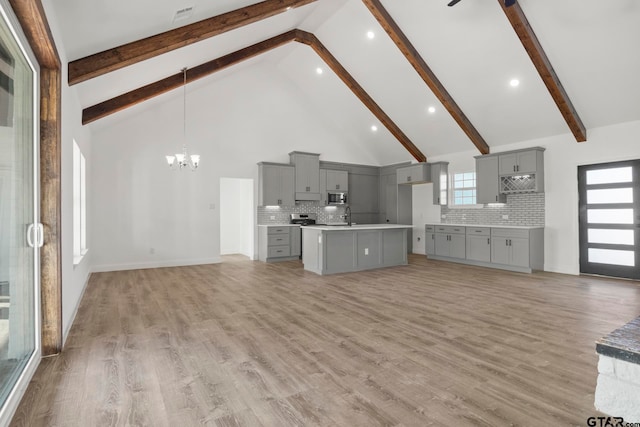 unfurnished living room featuring beamed ceiling, light hardwood / wood-style floors, high vaulted ceiling, and a healthy amount of sunlight