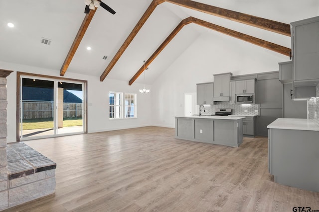 living room featuring beamed ceiling, ceiling fan with notable chandelier, light wood-type flooring, and high vaulted ceiling