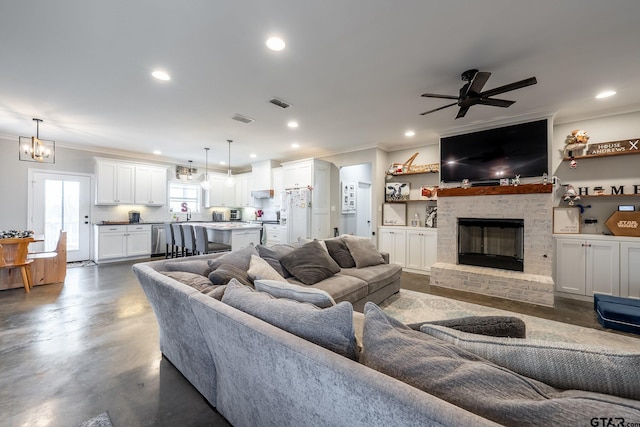 living room featuring a fireplace, ceiling fan with notable chandelier, and ornamental molding