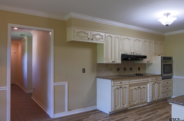 8310 Columbia Dr, Tyler, TX 75703 - kitchen featuring stainless steel oven, under cabinet range hood, black electric cooktop, decorative backsplash, and ornamental molding