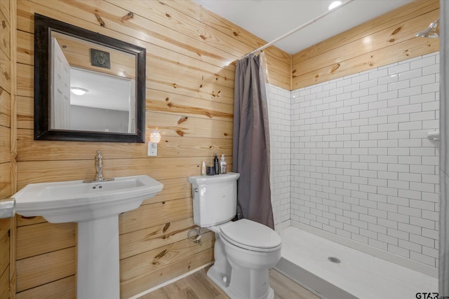 bathroom featuring wooden walls, curtained shower, hardwood / wood-style floors, and toilet