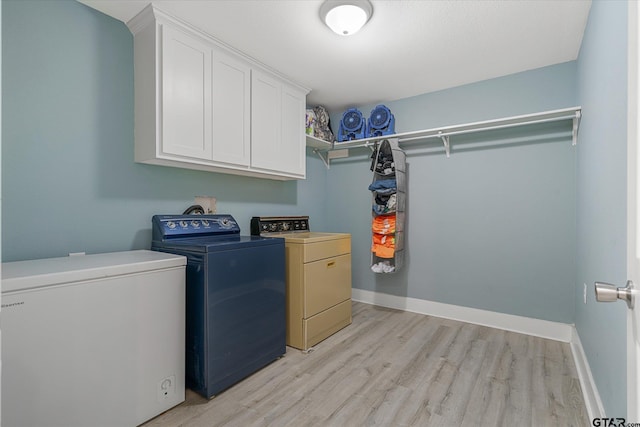 clothes washing area featuring cabinets, washing machine and dryer, and light wood-type flooring