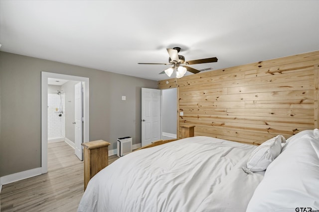 bedroom with light wood-type flooring, ceiling fan, and wood walls