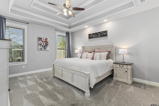 bedroom with ceiling fan, light colored carpet, multiple windows, and a tray ceiling