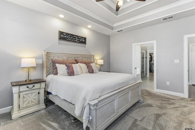 carpeted bedroom featuring ceiling fan, a tray ceiling, and ornamental molding