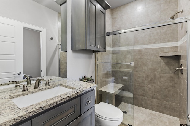 bathroom featuring a shower with shower door, toilet, and vanity