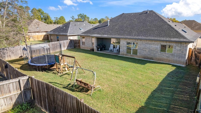 rear view of house with a playground, a patio area, a lawn, and a trampoline