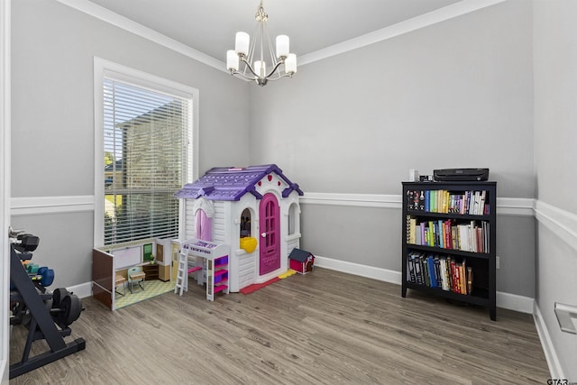 playroom featuring hardwood / wood-style flooring, crown molding, and a chandelier