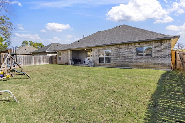 rear view of property featuring a yard, a playground, and a patio